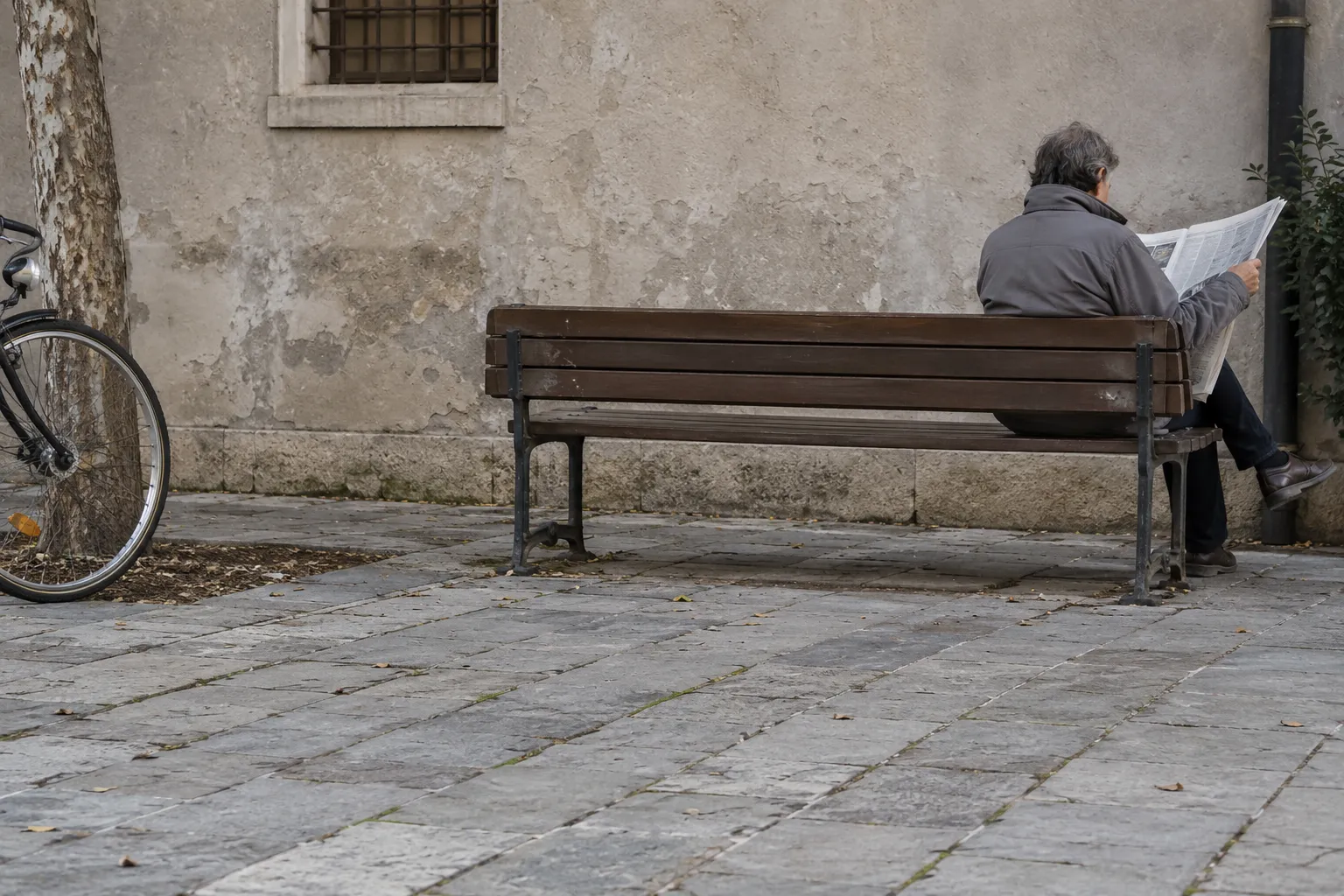 Eine erwachsene Person auf einer Bank vor einer rauen Wand.