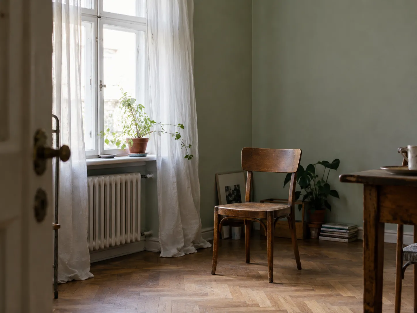 Heller Vorhang und alter Holzstuhl in einem schlichten Zimmer.